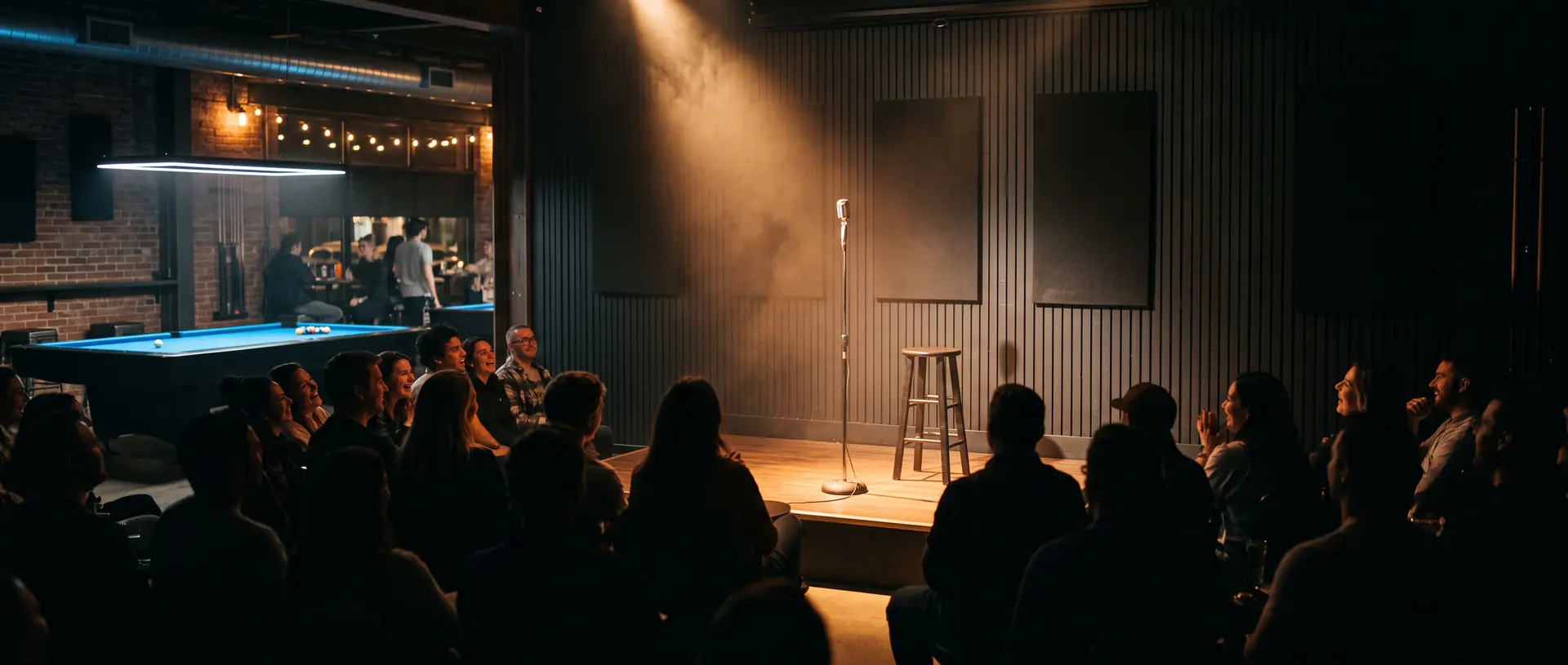 A spotlight falls on the microphone stand and stool at Komic Karma, the audience silhouetted in front